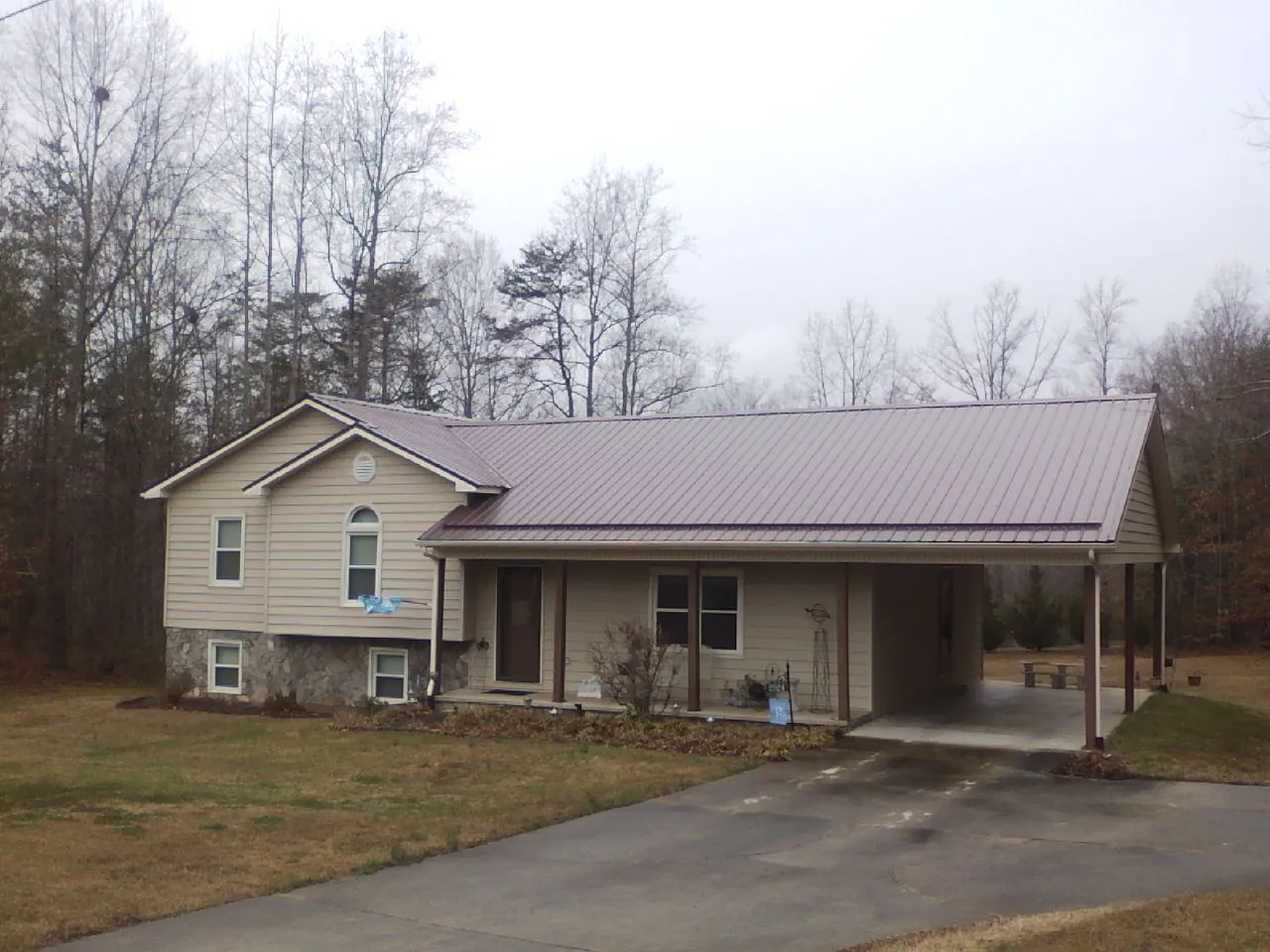 Burgundy metal roof on a tan split level home with an attached carport in Marshville