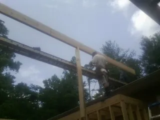 Carpenter setting a ridge beam over a new addition frame — Ice Dam Removal by Roofing Brothers in Marshville