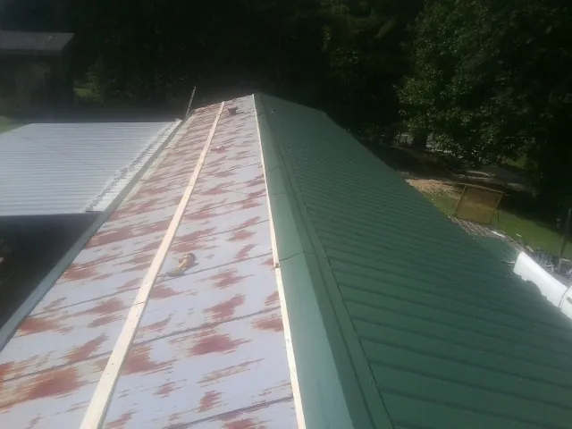 Old rusted panels beside newly installed green metal roofing — Wind Damage Roof Repair by Roofing Brothers in Marshville