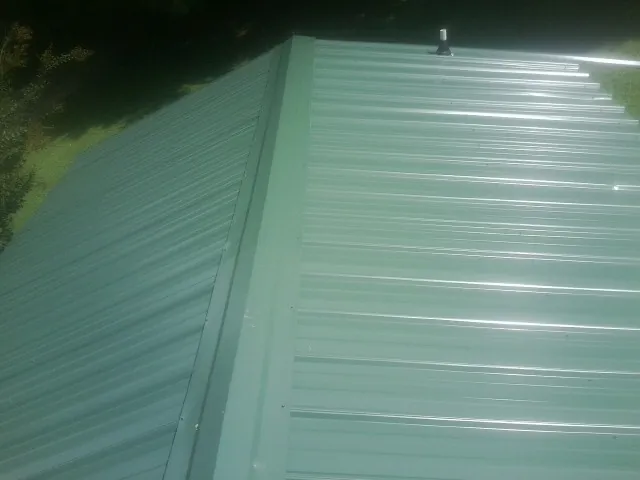 New green metal panels meeting at the ridge of a roof — Flat Roof Repair work by our crew in Marshville