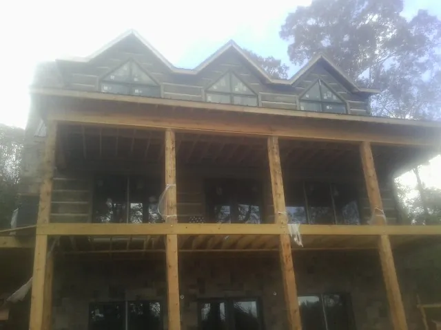 Dormers and porch framing on a large log home under construction — Roof Coating work by our crew in Marshville