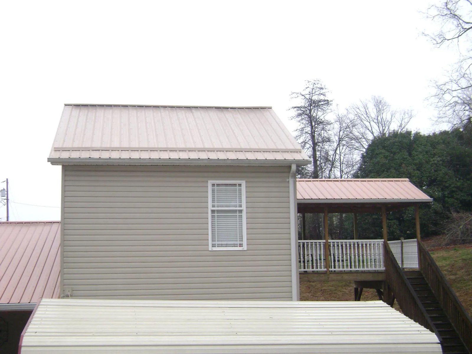 Tan metal roofs on a two story addition and attached porch, from a Roof Replacement job in Marshville