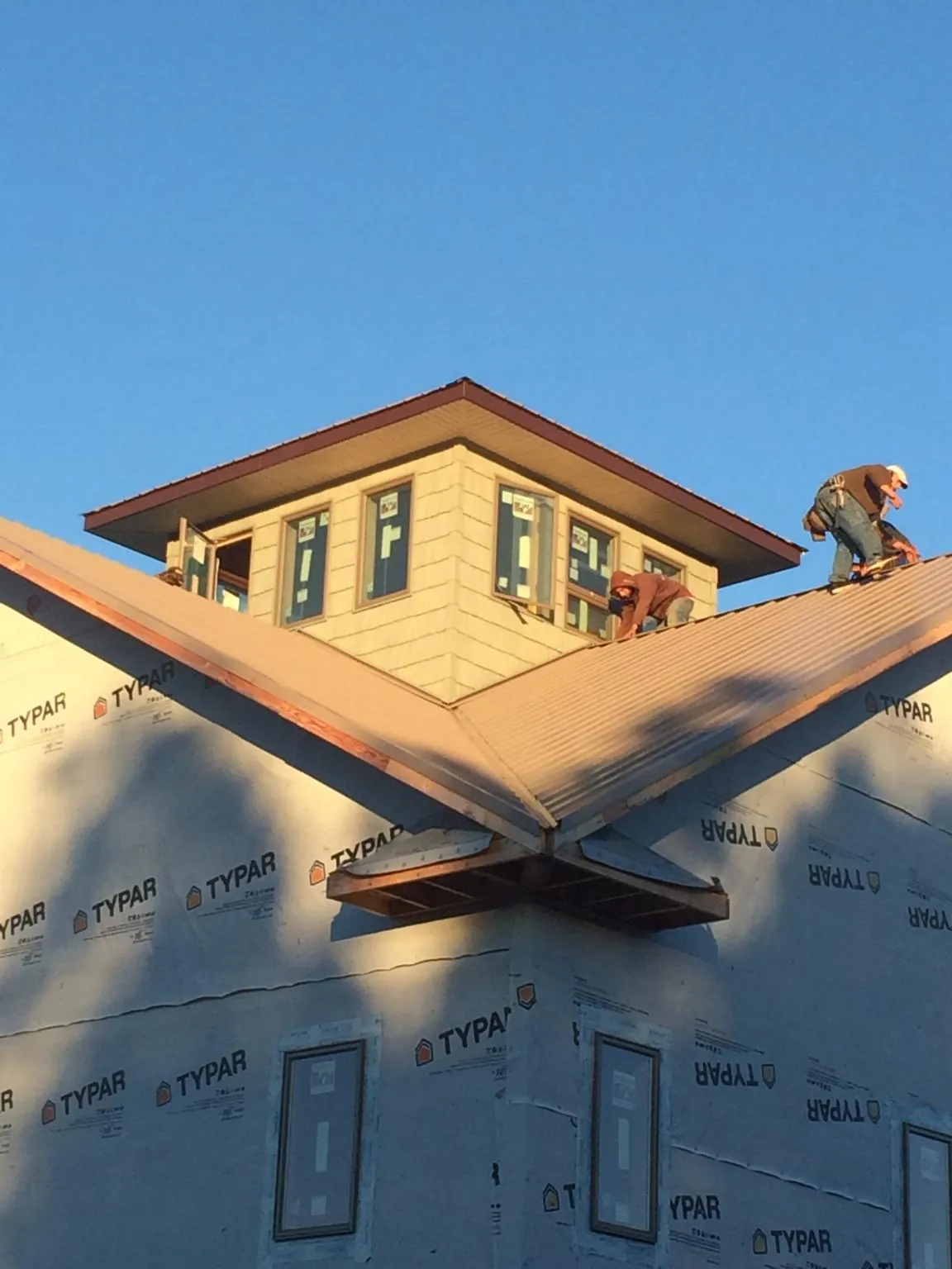 Roofers working around a rooftop cupola on a new metal roof at sunset — Roof Waterproofing in Marshville by Roofing Brothers